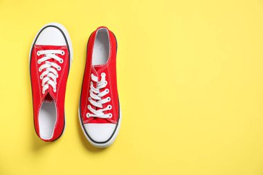 Sarı arka planda şık bir çift spor ayakkabı, üst manzara. Metin için boşluk