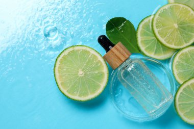 Bir şişe cilt bakımı ürünü, limon dilimleri ve açık mavi arkaplanda yeşil yaprak, düz bir zemin. Metin için boşluk