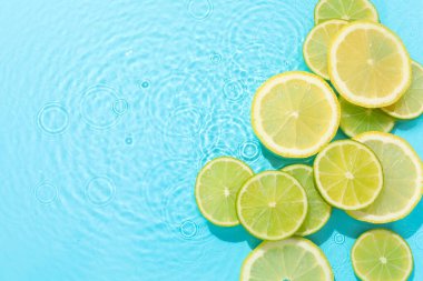 Açık mavi arka planda limon ve limon dilimleri, düz. Metin için boşluk