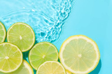 Açık mavi arka planda limon ve limon dilimleri, düz. Metin için boşluk