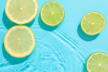 Açık mavi arka planda limon ve limon dilimleri, düz. Metin için boşluk