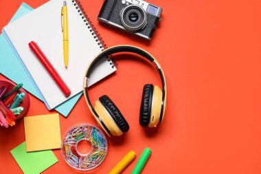 Kulaklıklar, klasik kamera ve turuncu arka planda kırtasiye malzemesi, düz konum. Metin için boşluk