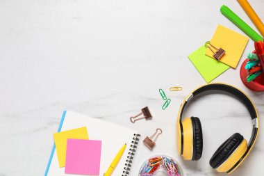 Kulaklıklar ve kırtasiye malzemeleri beyaz mermer masada, düz yerde. Metin için boşluk