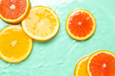 Turkuaz arka planda sudaki narenciye dilimleri, düzlük.