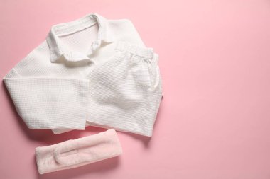 Pembe arka planda modaya uygun beyaz pijamalar ve saç bandı. Metin için boşluk