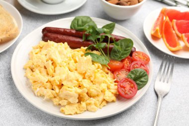 Lezzetli bir kahvaltı. Lezzetli çırpılmış yumurta, sosis ve domatesler gri desenli masa, yakın plan.