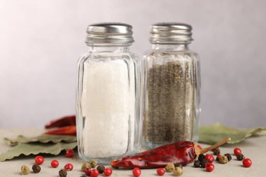 Açık gri masada baharatlı tuzluk ve biberlikler, yakın plan.