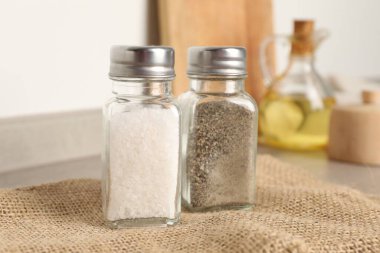 Beyaz duvarın yanındaki masada baharatlı tuzluklar ve biberlikler, yakın plan.