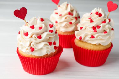 Sevgililer Günün kutlu olsun. Lezzetli çörekler ve beyaz ahşap masa üzerinde kalp şeklinde kaplar, yakın plan.