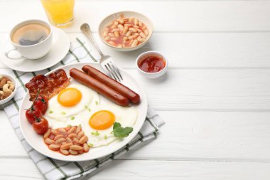 Geleneksel İngiliz kahvaltısı. Lezzetli, güneşli, domuz pastırmalı yumurta ve sosisler beyaz ahşap masada servis ediliyor, yakın plan. Metin için boşluk