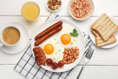 Geleneksel İngiliz kahvaltısı. Lezzetli, güneşli, domuz pastırmalı yumurta ve sosisler beyaz ahşap masada servis ediliyor.