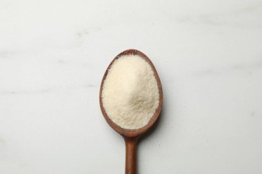 Beyaz masada kaşık içinde jelatin tozu, üst manzara.