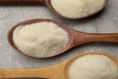 Açık gri masada, kaşıklarda jelatin tozu, düz yerde.