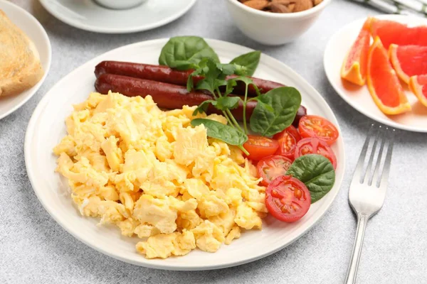 Lezzetli bir kahvaltı. Lezzetli çırpılmış yumurta, sosis ve domatesler gri desenli masa, yakın plan.