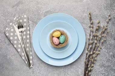 Paskalya kutlaması. Gri desenli masa üzerinde boyanmış yumurtalar ve söğüt dalları olan şenlikli bir yer.