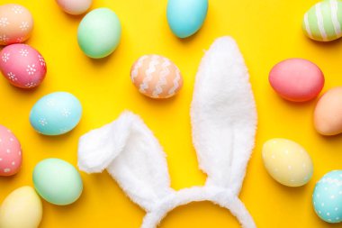 Mutlu Paskalyalar. Sevimli tavşan kulakları ve sarı arka planda boyanmış yumurtalar.