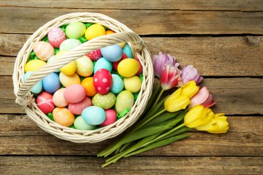 Tahta masanın üzerinde boyanmış yumurtalar ve laleler olan Paskalya sepeti, düz yatıyordu.