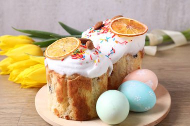 Lezzetli Paskalya pastaları, laleler ve ahşap masaya boyanmış yumurtalar, yakın plan.