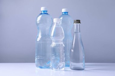 Beyaz masada gri arka planda farklı boyutlarda su şişeleri