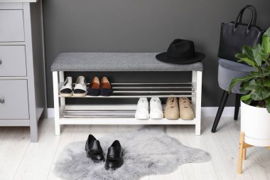 Gri duvarın yanında farklı ayakkabı ve aksesuarlarla dolu bir ayakkabı deposu.