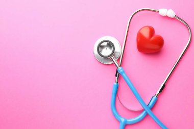 Pembe arka planda steteskop ve kırmızı kalp. Metin için boşluk