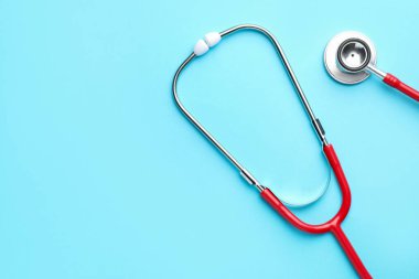 Açık mavi arka planda kırmızı steteskop, üst manzara. Metin için boşluk