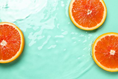Turkuaz arka planda greyfurt dilimleri, düz bir zemin. Metin için boşluk