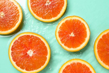 Turkuaz zemin üzerinde suda greyfurt dilimleri, düz yatış