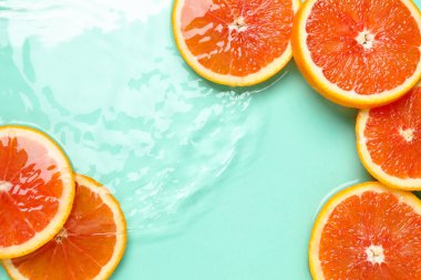 Turkuaz arka planda greyfurt dilimleri, düz bir zemin. Metin için boşluk
