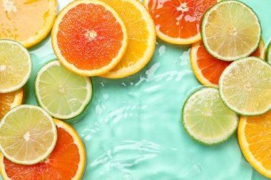 Turkuaz arka planda sudaki narenciye dilimleri, düzlük.