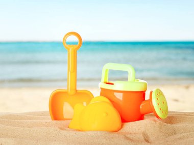 Deniz kenarındaki kumda parlak plastik plaj oyuncakları. Yaz zamanı.