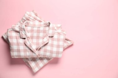 Pembe arka planda moda damalı pijamalar, üst manzara. Metin için boşluk