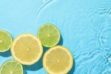 Açık mavi arka planda limon ve limon dilimleri, düz. Metin için boşluk