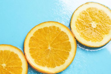 Açık mavi zemin üzerinde portakal dilimleri, düz uzanmış.