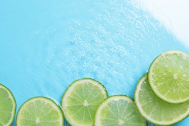 Açık mavi arka planda limon dilimleri, düz bir zemin. Metin için boşluk