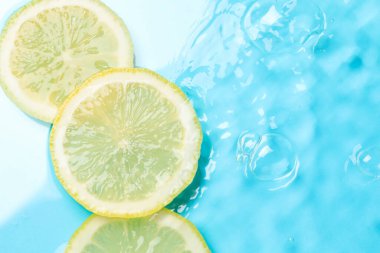 Açık mavi arka planda limon dilimleri, düz. Metin için boşluk