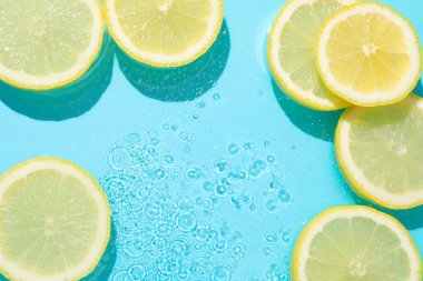 Açık mavi arka planda limon dilimleri, düz. Metin için boşluk