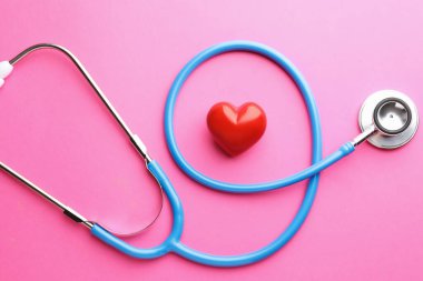 Pembe arka planda steteskop ve kırmızı kalp, düz yatıyordu.