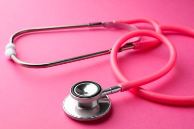 Pembe arka planda bir steteskop, yakın plan. Tıbbi araç