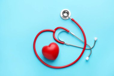 Açık mavi arkaplanda kırmızı steteskop ve kalp modeli.