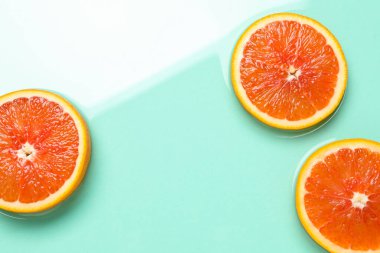 Turkuaz arka planda greyfurt dilimleri, düz bir zemin. Metin için boşluk