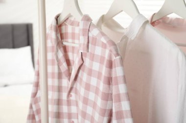Yatağın yanındaki askıda asılı şık pijama gömlekler, yakın plan.