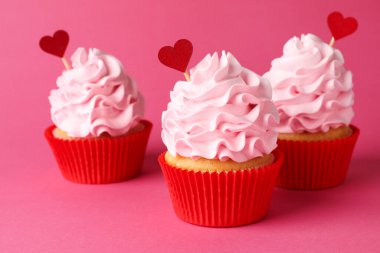 Sevgililer Günün kutlu olsun. Pembe arka planda kırmızı kalp kaplamalı lezzetli kekler, yakın plan.