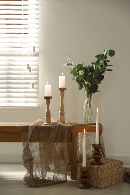 Zarif şamdanlar, yanan mumlar ve kapalı masa üzerinde dalları olan vazolar.