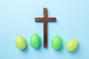 Ahşap haç ve açık mavi arka planda Paskalya yumurtaları, düz yatıyordu.