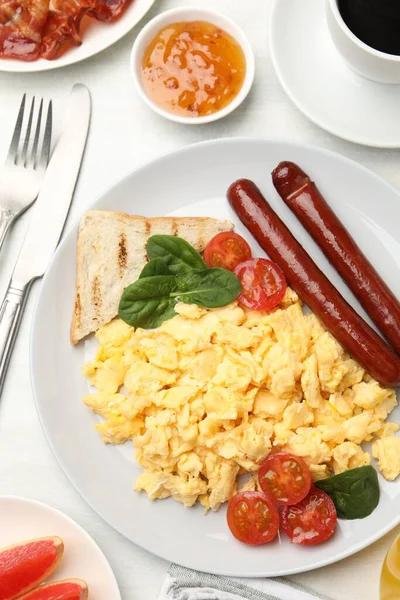 Lezzetli bir kahvaltı. Nefis çırpılmış yumurta, sosis ve domatesle servis edilmiş, düz bir masa.