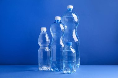 Mavi arka planda farklı boyutlarda su şişeleri