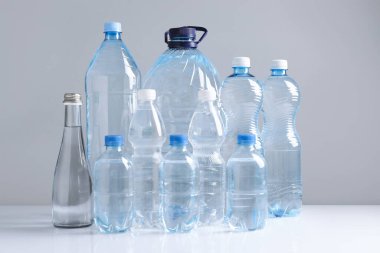 Beyaz masada gri arka planda farklı boyutlarda su şişeleri