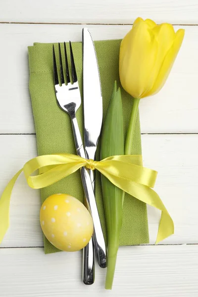 Paskalya sofrası. Beyaz ahşap arka planda lale ve boyalı yumurta ile güzel gümüş takımlar, üst manzara.