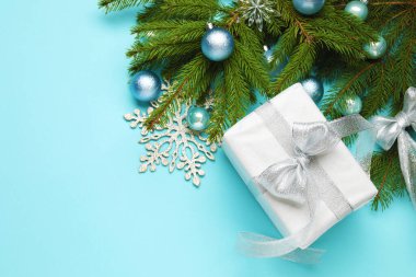 Hediye kutusu ve açık mavi arkaplanlı dekorlu Noel kompozisyonu. Metin için boşluk